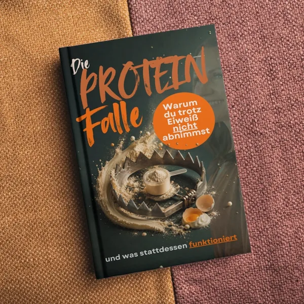 Buch mit dem Titel „Die Protein Falle“ zeigt eine Bärenfalle mit Proteinpulver, Eierschalen und Sahne, dazu der Text: „Warum du trotz Eiweiß nicht abnimmst“.